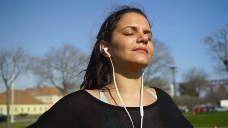 Sportliche-Junge-Frau-Mit-Kopfhörern-Meditiert-Im-Park